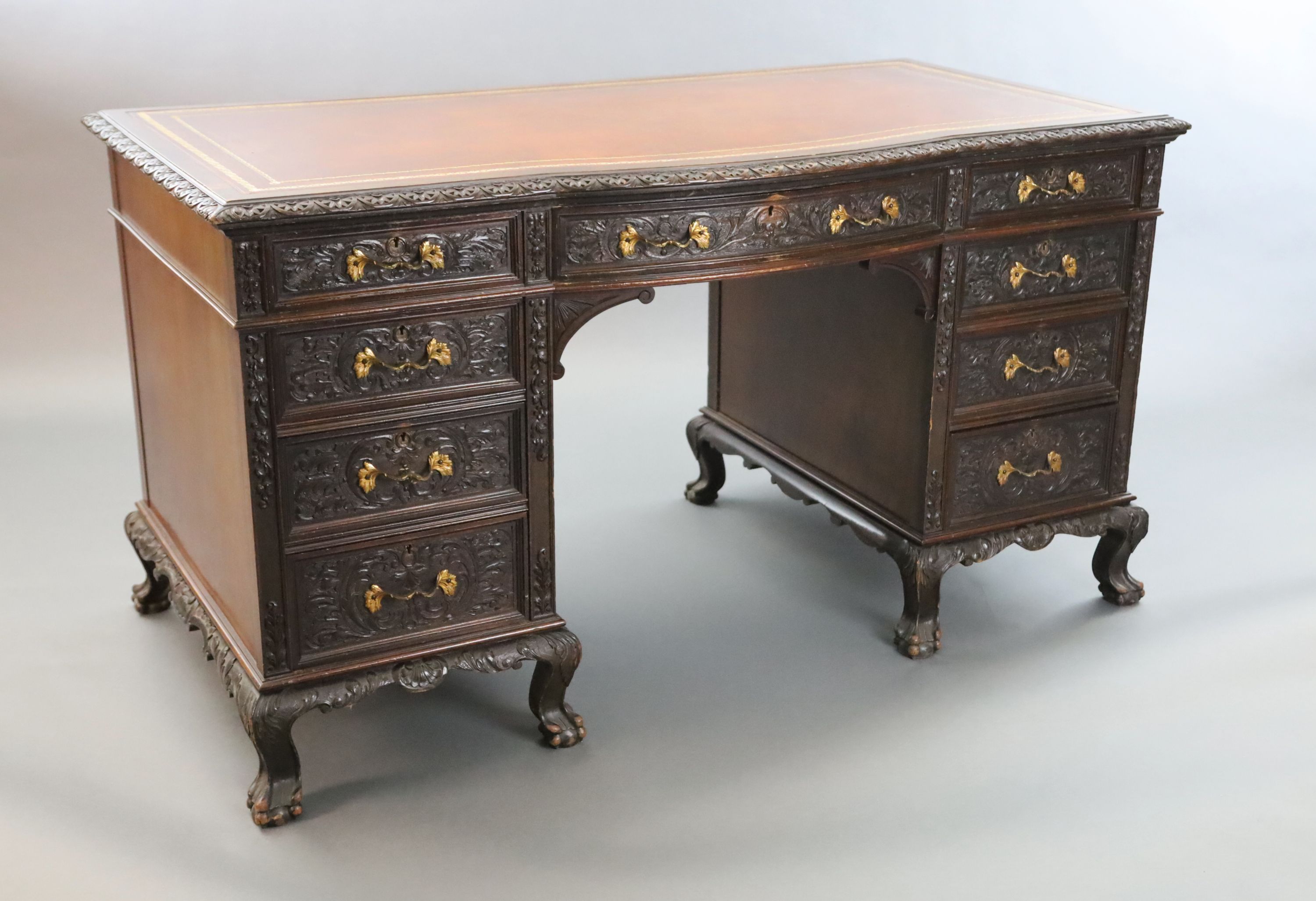 An Edwardian foliate carved mahogany serpentine kneehole desk, W.4ft 6in. D.2ft 5in. H.2ft 6in.